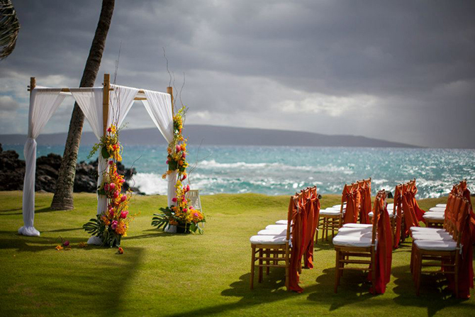 Purple orchid Wedding - White drapery arch with magenta and yellow florals seaside