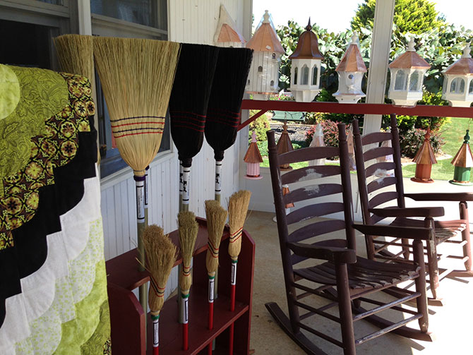 The Inn At Leola Village rocking chairs on porch with handmade brooms and wooden bird houses