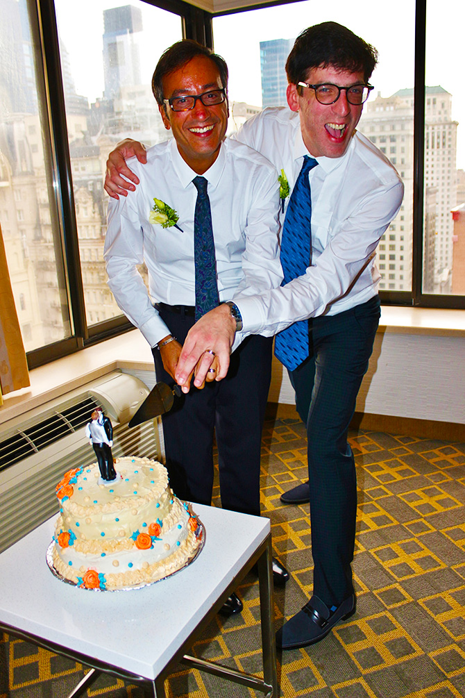 Two grooms showing off their new wedding rings and wedding cake - Four Directions Ceremonies Susan E. Stein LGBT Wedding Officiant in PA