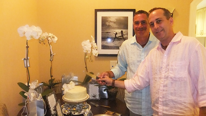 Two casual grroms with small wedding cake and white orchids - Four Directions Ceremonies Susan E. Stein LGBT Wedding Officiant in PA